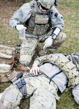 United States Army ranger treating the wounds of his injured fellow in arms
