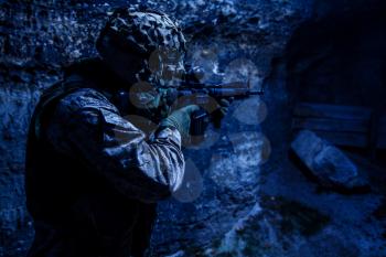 US Marine Corps Soldier in action among the rocks under cover of darkness. Dark gloomy night