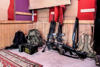 U.S. army marines assault squad weapon storage at outpost with service rifles, combat shotgun, tactical backpacks and ammunition boxes, sniper rifle with optical sight and machine gun with ammo belt