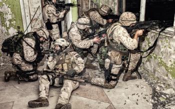 Special operations forces soldiers team, commando assault squad keeping defense under fire in abandoned building, restraining and attacking enemy, calling for reinforcements or evacuation with radio