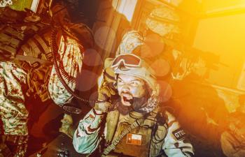 Commando team leader, counter terrorist squad officer, military operator screaming in radio handset while calling for reinforcements, evacuation or artillery support during intensive night firefight