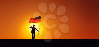 Silhouette of USA armed forces soldier, army infantryman or Marine Corps fighter saluting while standing with waving national flag on sunset background. Military victory and glory, fallen remembrance
