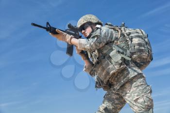 Portrait of United states airborne infantry female with arms, camo uniforms dress. Combat helmet, backpack rucksack, low angle
