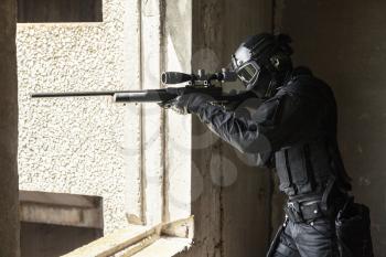 Swat police operator with sniper rifle in black uniforms aiming criminals terrorists from the window