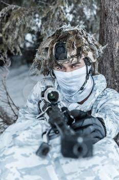 Winter arctic mountains warfare. Action in cold conditions. Sniper with weapons in forest somewhere above the Arctic Circle