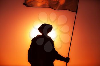 Silhouette of army soldier, commando fighter special forces infantryman standing on background of sunset sky waving on flagpole flag. Military victory, remembrance of fallen soldiers, veterans concept