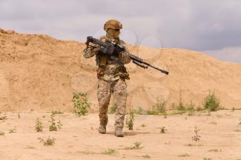 Equipped and armed special forces soldier with rifle in the desert during the military operation.