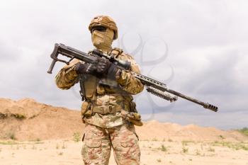 Soldier in camouflage holding sniper rifle close-up
