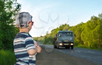 The little boy looks at the moving car