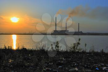 Power plant in beams of the coming sun. In the foreground it is a lot of garbage.