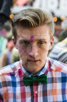 Lviv, Ukraine - August 30, 2015: Man with bow tie  watches festival of colors in a city park in Lviv.