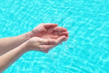 Human hands with clear water on the blue background