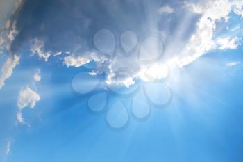 Beautiful blue sky with sunbeams and clouds. Sun rays.