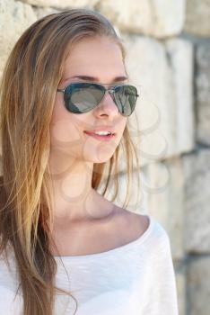 Beautiful blond girl in the goggles against the ancient wall