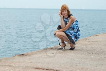 Beautiful woman sitting on the mooring with blue background