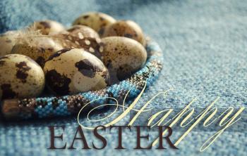 Easter composition with feather, quail eggs and beaded jewellery on woolen fabric. Close up.