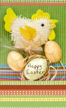 Easter composition with eggs and handmade toy chicken on a green and ornamental cloth. 