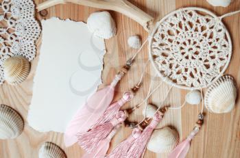 Seashells frame on wooden background with place for text. Card for a beach party, invitation, advertising. Dreamcatcher with pink feathers