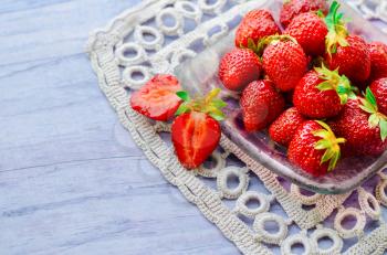 Fresh strawberries in a bowl on wooden table.