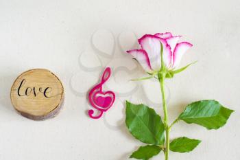 Rose with a pink heart and with love written on a piece of wood. ose with a decorative heart in the shape of a treble clef with pink felt. Valentine's day, mother's day congratulation