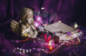 Composition with a golden Cupid, a gift box, a heart in a mystical dark light. Valentine's Day