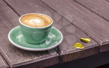Turquoise Latte Cup on a wooden background with golden hearts. Still Life to Valentine's Day.