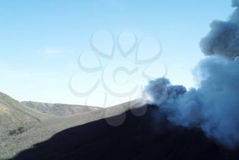 Smoke from the mouth of the volcano. Eruption. Clubs of smoke and ash in the atmosphere.