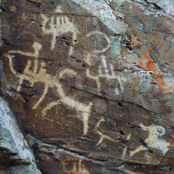 Hunting scenes palaeolithic Petroglyphs carved in rocks. Hunters on camels. Stones with petroglyphs in the Chuya Steppe, Kuray steppe in the Siberian Altai Mountains, Russia