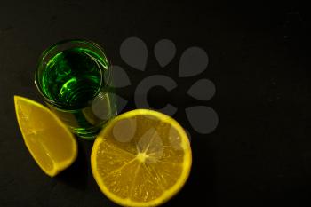 Absinthe and lemon on black background. Alcohol drink. Green alcohol drink