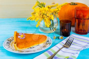 Thanksgiving pumpkin pie slice on the blue wooden table. Traditional Thanksgiving pumpkin pastry.