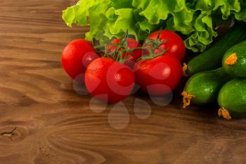 Tomato, cucumber and lettuce on rustic wooden background. Healthy eating concept with fresh vegetables. Vegetarian  vegan food background. Copy space.
