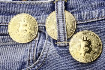 Three golden bitcoins on the jeans pants. Making online money concept. How to make money conceptual image. Mining golden bitcoins on the internet. Easy money on the internet concept.