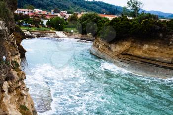 Astonishing landscape of waves crashing into breakwaters with a two storey blank house in the background. Gorgeus Ocean Surrounded by cliffs and prominent green bushes. 