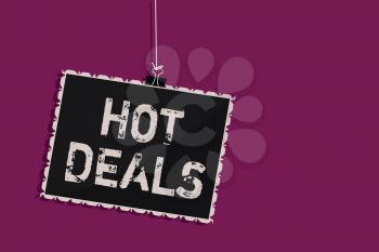 Word writing text Hot Deals. Business concept for An agreement through which one of the paties is offered and accept Hanging blackboard message communication information sign purple background