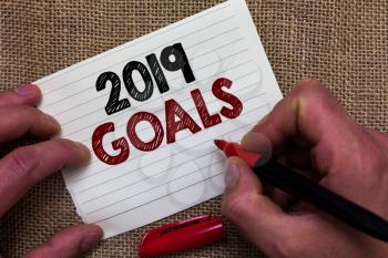 Writing note showing 2019 Goals. Business photo showcasing A plan to do for something new and better for the coming year Man's hand hold white paper with symbolic letter jute sack background