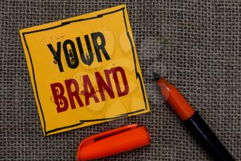Conceptual hand writing showing Your Brand. Business photo showcasing A name of any kind that is impacted to something as trademark Orange paper Marker Communicate ideas Jute background