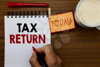 Text sign showing Tax Return. Conceptual photo which taxpayer makes annual statement of income circumstances Man holding marker notebook clothespin reminder wooden table cup coffee