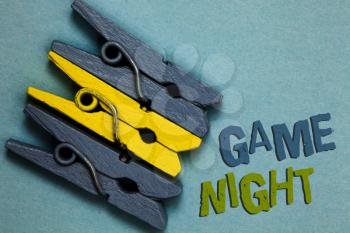 Conceptual hand writing showing Game Night. Business photo text event in which folks get together for the purpose of getting laid Gray yellow vintage clothespins clear background Holding things