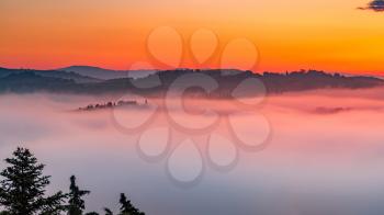 Early morning mist flooding the valleys of Tuscany at sunrise