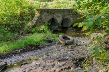 Large old concrete drain pipe, culvert in the grass.
