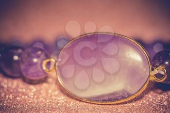 Fashion bracelet made of natural purple amethyst beads, filtered background.