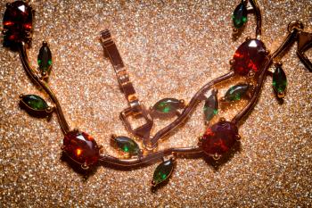 Decorative rose gold bracelet with ruby red and green zircons, floral themed jewellery.