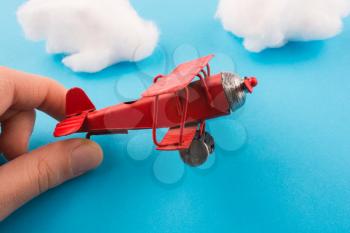 Retro styled red model airplane in hand, blue sky and clouds