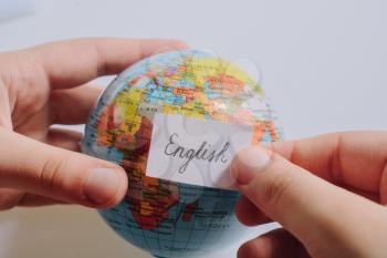 Hand holding notepaper with English wording on model globe