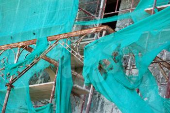 Abandoned mansion renovation. Vintage rusty metal shed and torn scaffold debris netting.