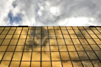Sky mirrored on the glass windows of a modern office building. Architectural detail.