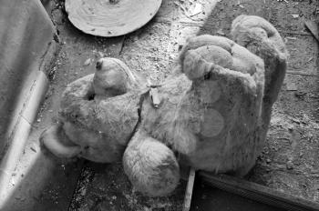 Vintage teddy bear on the dirty floor of an abandoned house. Black and white.