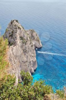 View to the ionian sea and small boat cruising through the Myzithres rocks. Zakynthos, Greece.