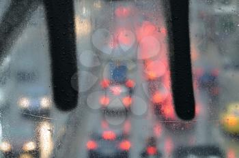 Raindrops macro on glass overpass surface and blurry city traffic lights.