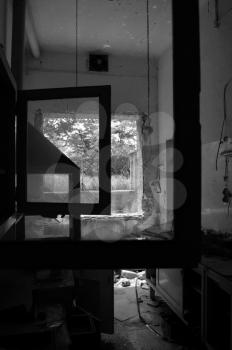 Broken window frames and reel tape on abandoned factory floor. Black and white.